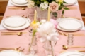 Wedding table with blush pink cloth, gold cutlery and white and peach roses in the centre
