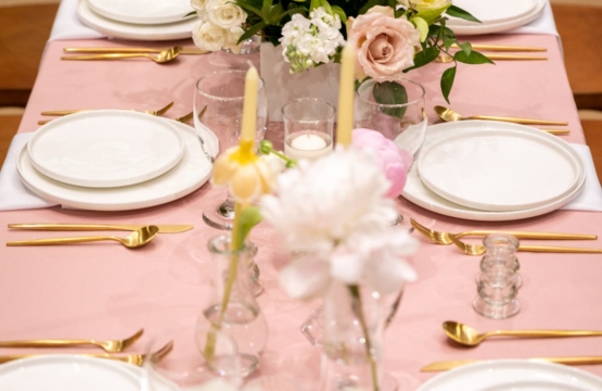 Wedding table with blush pink cloth, gold cutlery and white and peach roses in the centre