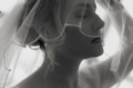 Black and white wedding portrait of a bride lifting her veil in soft window light